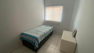 a small room with a bed and a window at Apartamento Daia Prox Caoa in Anápolis