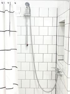 prysznic z wężem w wyłożonej białymi kafelkami łazience w obiekcie Casa Veronica 3 , 1 dormitorio w mieście Las Galletas