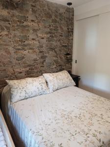 1 cama en un dormitorio con pared de ladrillo en Naturaleza viva, en San Martín de Valdeiglesias
