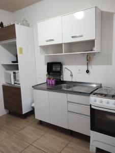 a kitchen with white cabinets and a sink and a stove at FLORIPA FLORINDO APART in Florianópolis