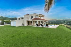a large white house with chairs on a lawn at Casa Cielo in Rincon