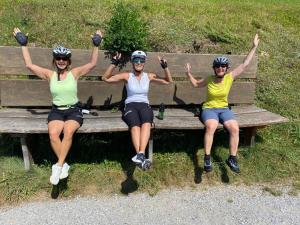 drei Frauen sitzen auf einer Bank mit den Händen in der Luft in der Unterkunft Ferienwohnung Waldblick in Kramsach
