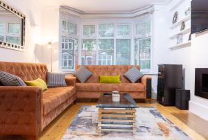 a living room with a brown couch and a tv at Mapperley Park Guesthouse in Nottingham