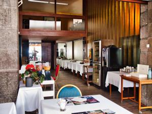 a restaurant with white tables and chairs and a kitchen at Hôtel de Paris in Châtel-Guyon