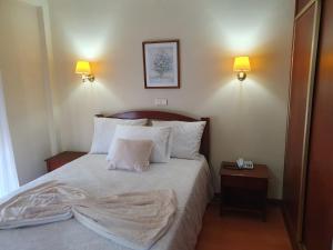 una camera da letto con letto, lenzuola e cuscini bianchi di Hotel Peninsular a Monte Real