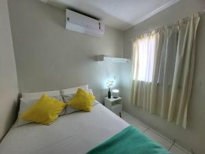 a bedroom with a bed with yellow pillows and a window at Teto Hospedagens in Fortaleza