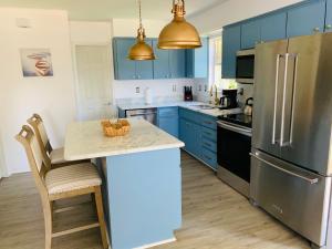 a kitchen with blue cabinets and a stainless steel refrigerator at Beachfront House Pine Island, Tampa, Orlando in Weeki Wachee