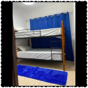 a bunk bed with a blue curtain and a blue rug at Apartment city center of puerto Plata in San Felipe de Puerto Plata