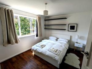 ロンドンにあるCharming 2-Bed Garden Flatの白いベッドルーム(ベッド1台、窓付)