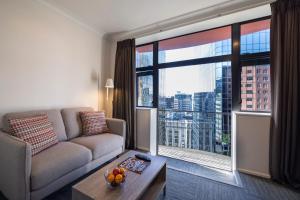 a living room with a couch and a large window at Quest On The Terrace Serviced Apartments in Wellington