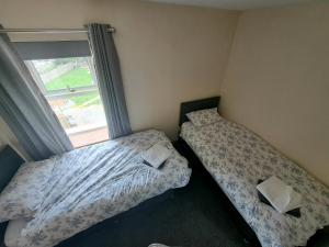 two beds in a room with a window at Rose Cottage Trecynon Traditional 2 bed cottage Zip World Beacons Bike in Aberdare