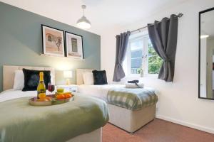 a bedroom with two beds and a bottle of wine at Appledore House - Close to City Centre - Free Parking, Fast Wifi, Private Garden and Smart TV with Netflix by Yoko Property in Milton Keynes
