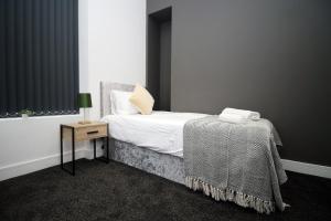 a bedroom with a bed and a table with a night stand at Skyline Remarkable 2-Bed Apartment in Swansea in Swansea