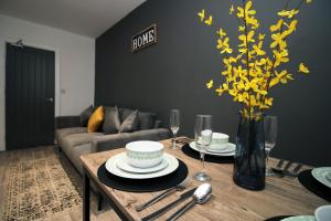 a living room with a table with yellow flowers in a vase at Skyline Remarkable 2-Bed Apartment in Swansea in Swansea