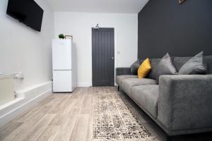 a living room with a gray couch and a refrigerator at Skyline Remarkable 2-Bed Apartment in Swansea in Swansea