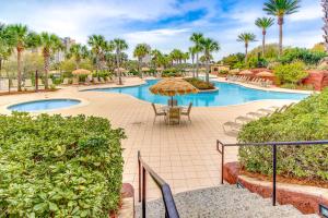 a resort with a pool with chairs and umbrellas at Luau 6909 in Destin