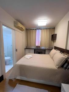 een slaapkamer met een wit bed en een badkamer bij Loft Premier Centro e 800 mt da Oktoberfest. in Blumenau