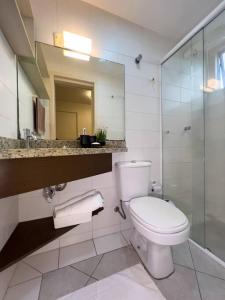 een badkamer met een toilet, een wastafel en een spiegel bij Loft Premier Centro e 800 mt da Oktoberfest. in Blumenau