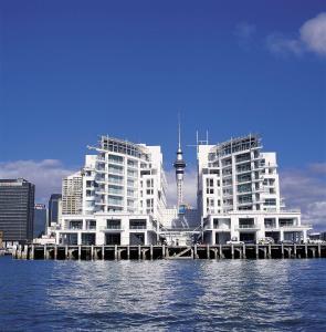 twee hoge witte gebouwen op het water met een stad bij Hilton Auckland in Auckland