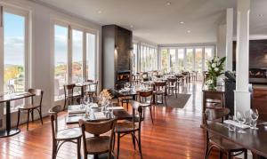 a restaurant with tables and chairs and windows at Hilton Lake Taupo in Taupo