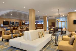 Hilton Baltimore BWI Airport في لينثيكوم هايتس: غرفة معيشة مع أريكة بيضاء وطاولات وكراسي