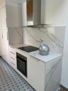 een witte keuken met een vaas op het aanrecht bij THE ORANGE TREE HOUSES - Terraço by Live and Stay in Abrantes