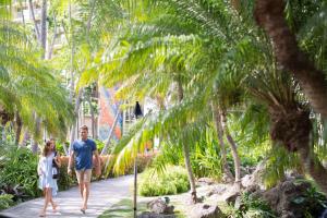 a man and a woman walking through a garden at Hilton Hawaiian Village Waikiki Beach Resort in Honolulu