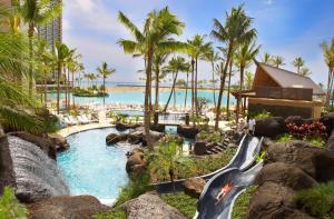 een zwembad met een waterval en een waterglijbaan bij Hilton Hawaiian Village Waikiki Beach Resort in Honolulu