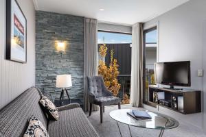 a living room with a couch and a television at DoubleTree by Hilton Queenstown in Queenstown
