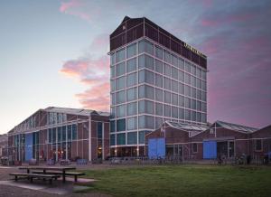 un edificio alto con un tavolo da picnic di fronte di DoubleTree by Hilton Amsterdam - NDSM Wharf ad Amsterdam