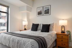 a white bedroom with a bed and two lamps at Prime Village Ski In Ski Out Location by Harmony Whistler in Whistler