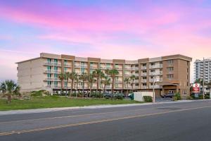 a building with palm trees in front of a street at Best Western Plus Daytona Inn Seabreeze in Daytona Beach