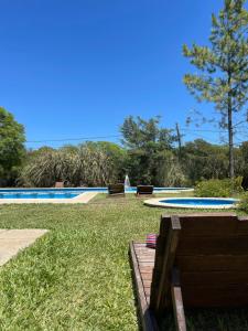 una piscina en un patio con césped y 2 bancos en don isidro habitacion matrimonial en La Paz
