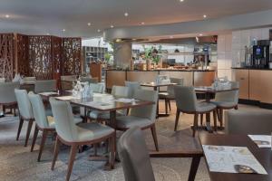 a restaurant with tables and chairs and a kitchen at Hilton Cambridge City Centre in Cambridge