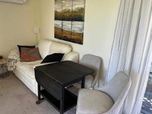Riverside Bliss في Clive: غرفة معيشة مع أريكة وطاولة وكرسيين