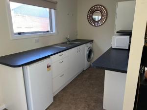 een keuken met een wastafel en een wasmachine bij Riverside Bliss in Clive