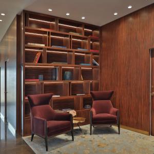 a library with two chairs and a table and shelves at The Plaza Doha, LXR Hotels & Resorts in Doha
