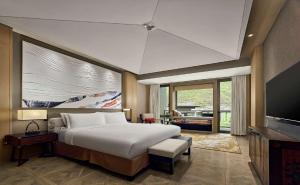 una camera con un grande letto e una televisione di Conrad Jiuzhaigou a Valle del Jiuzhaigou