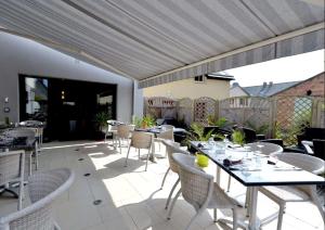 a patio with tables and chairs on a patio at Hotel le Broceliande - Sure Hotel Collection by Best Western in Bédée