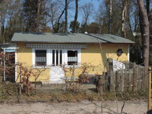格洛韋的住宿－Ferienhaus Am Dünenwald，围栏后面的一个小黄白色房子