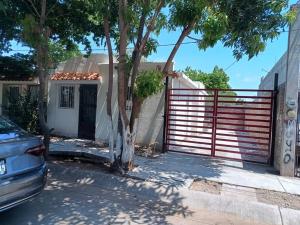 a fence in front of a house with a tree at Casa Villa (facturamos) in Los Mochis