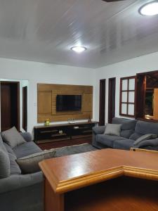 sala de estar con sofás y TV de pantalla plana. en Casa Maciel, en São Thomé das Letras