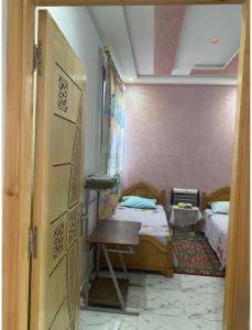 Habitación con 2 camas, mesa y puerta en Sabar house, en Tánger