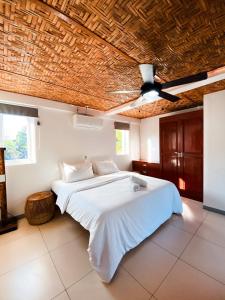 a bedroom with a white bed with a wooden ceiling at In Dai Aquasports and Beach Resort in Bantayan Island