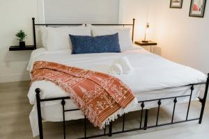 a bed with white sheets and blue pillows at Charming Kelowna Haven with Hot Tub, Parking, Pet-Friendly Bliss in Kelowna