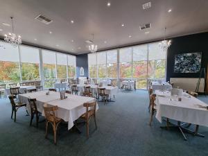a dining room with tables and chairs and large windows at Tumbarumba Motel & Elms Restaurant in Tumbarumba