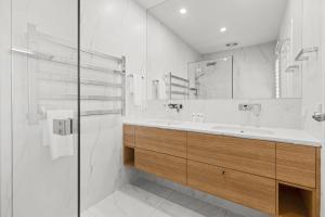 a white bathroom with a sink and a mirror at Noosa Outrigger Beach Resort in Noosaville