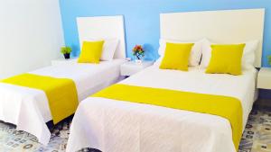 2 camas con almohadas amarillas en una habitación en Believer Hostel en Santa Marta