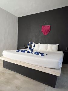 a large bed in a room with a pink towel on the wall at Kin studios holbox in Holbox Island