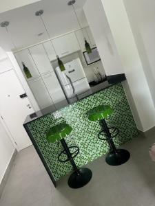 una cocina con dos taburetes verdes junto a un mostrador en Apartamento Olof, en Río de Janeiro